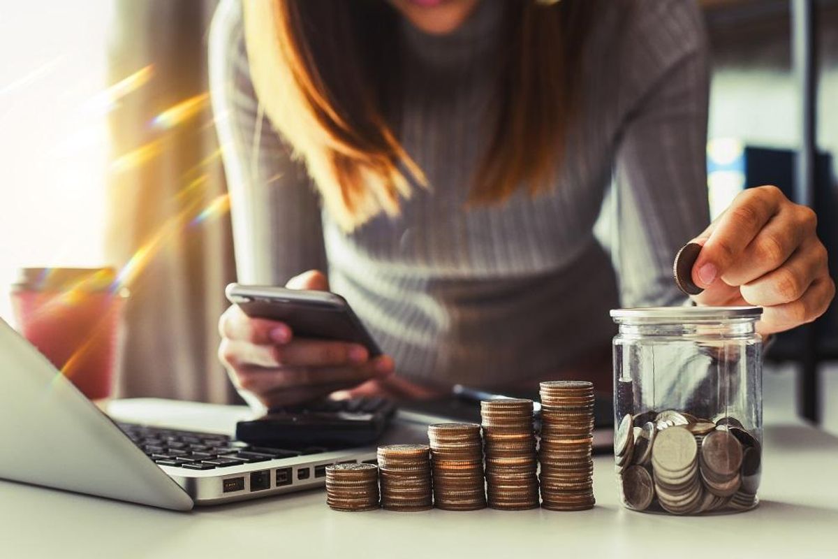 businesswoman putting coins in glass