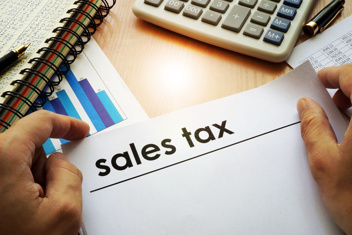 Hands holding documents with title sales tax