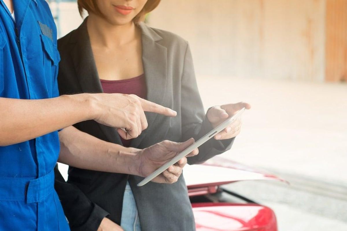 Skilled trade worker shows report on tablet to woman