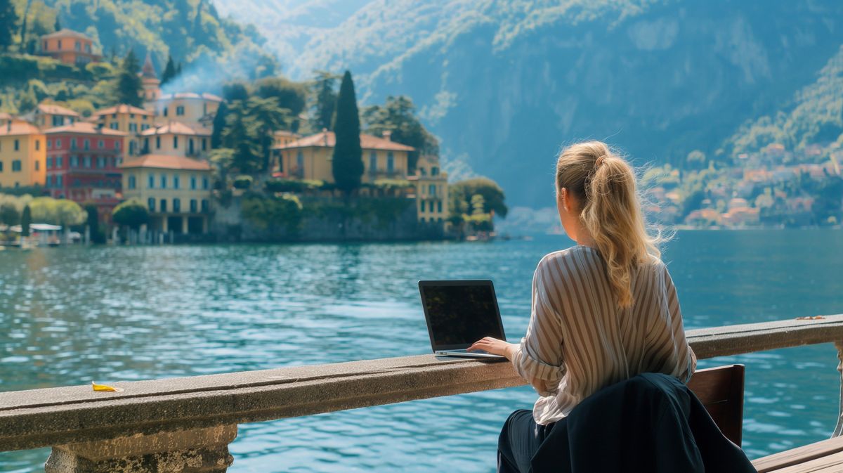 Young woman working remotely by a scenic lake in Italy, calm and focused